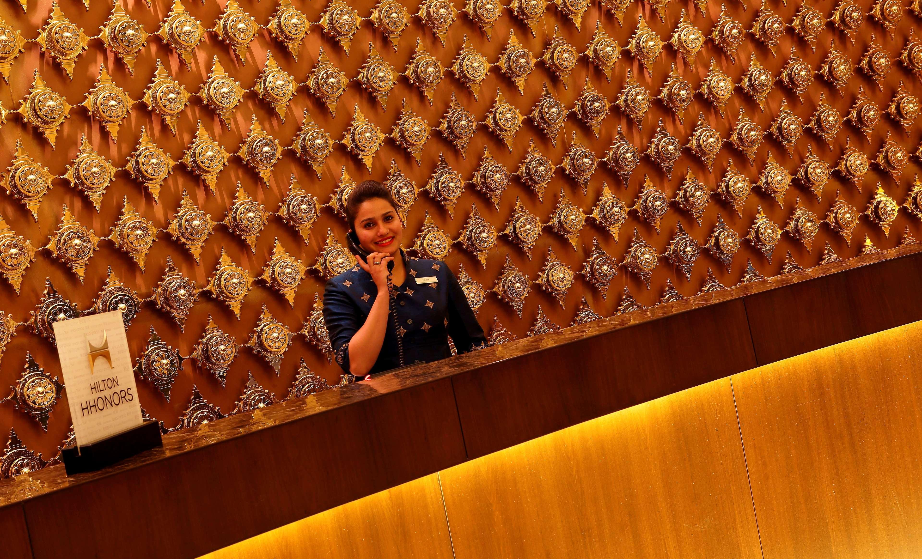 Hilton Jaipur Otel Dış mekan fotoğraf A hotel receptionist at work
